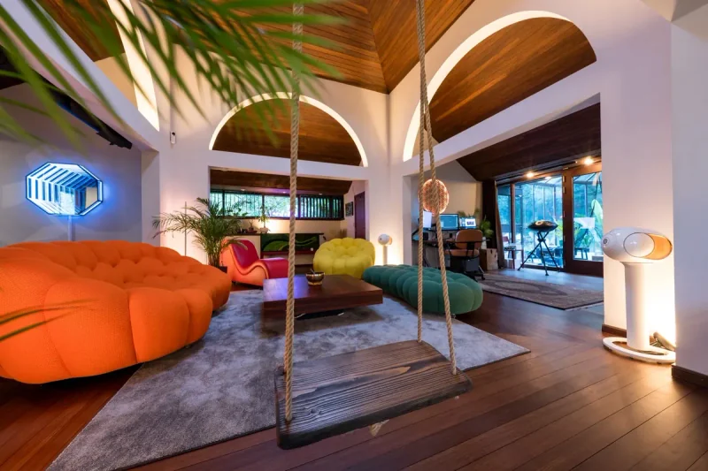 De lounge van de Kanaftchian-studio met een oranje Bubble-zitbank, gele, groene en rode zitmeubels en een schommel.