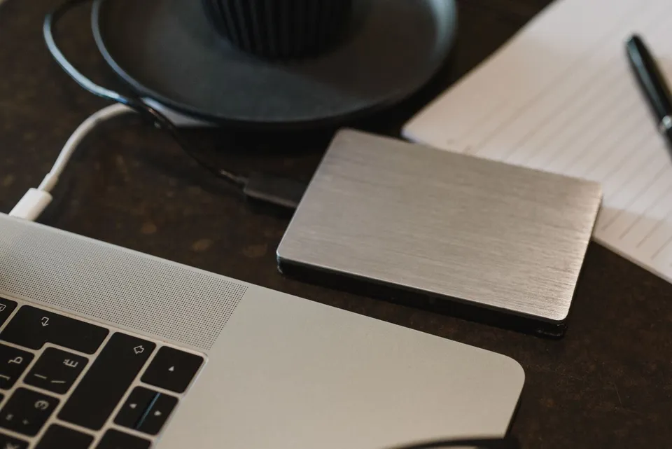 Un disque externe relié à un ordinateur portable sur un bureau.